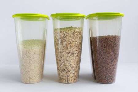 various groats in containers or jars on a white background. Rice, oatmeal and buckwheat