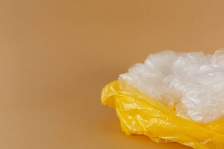 transparent and yellow disposable plastic bags on a brown background. Ecology and trash