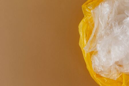 transparent and yellow disposable plastic bags on a brown background. Ecology and trash