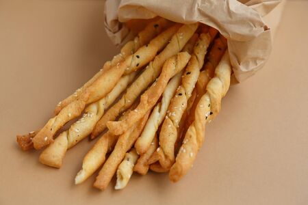 Crispy snack in a paper bag. Salty sesame bread sticks for a quick bite