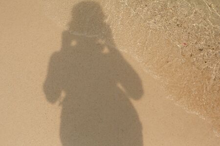 Shadow of a man on the sandy shore of a sea beach in the waves of water. Natural background.の写真素材