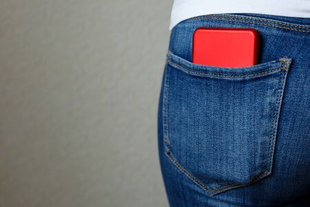 red smartphone in the back pocket of blue jeans close up