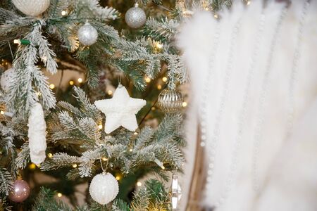 White Christmas toy hanging on a green snowy fir branch, closeupの写真素材