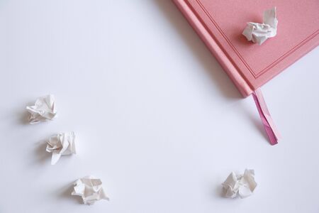 Pink diary on a white background and crumpled pieces of paper. Mistakes in the letterの写真素材