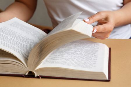 A woman is reading a book. Hands are holding a book. Beautiful manicure. A student is studying a...