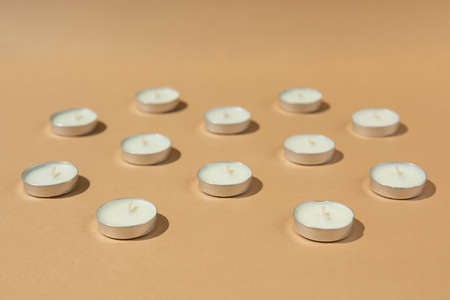 white candles on a beige background. Contrast lighting. side view.の写真素材