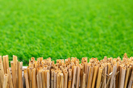 Fence made of dry bamboo stalks against a background of green artificial lawn grass. template for placing products or text. Backdrop or background.の写真素材