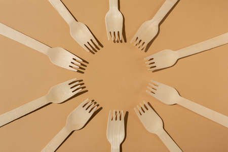 wooden forks are laid out in a circle. Contrast lighting. Flat lay. Eco friendly wooden cutlery. Plastic Free Concept.の写真素材