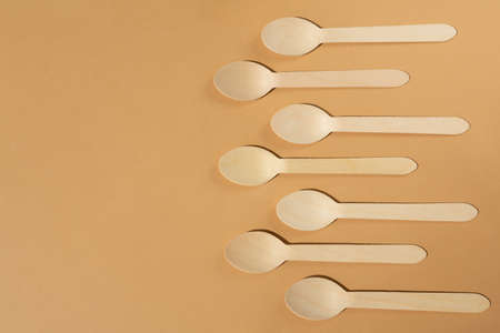 Wooden spoons on a beige or brown background. Contrast lighting. Flat lay. Eco friendly wooden cutlery. Plastic Free Concept.の写真素材