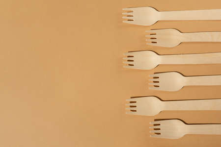 Wooden forks on a beige or brown background. Contrast lighting. Flat lay. Eco friendly wooden cutlery. Plastic Free Concept.の写真素材