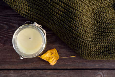 knitted clothes and candle in bank on wooden bench. Autumn Warm Woolen Sweater.の写真素材