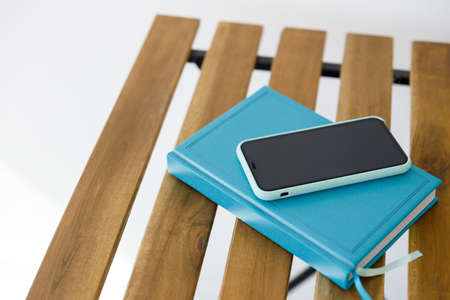 smartphone and notebook for planning affairs lie on wooden table against white wall backgroundの写真素材
