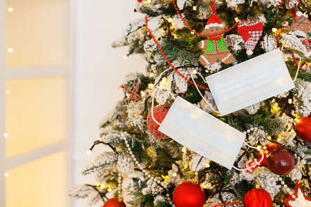 New Year and Christmas background. Protective medical face mask hanging on decorated christmas treeの写真素材