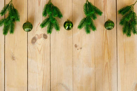 New Year and Christmas background. Artificial green spruce branches and Christmas tree toys balls on rough light yellow wooden boards. Floor covering. Place for text and goods, copy spaceの写真素材