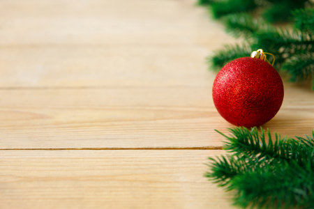 New Year and Christmas background. Artificial green spruce branches and Christmas tree toys balls on rough light yellow wooden boards. Floor covering. Place for text and goods, copy spaceの写真素材