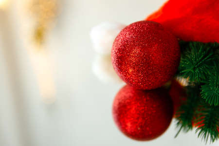 New Year and Christmas background. A red hat or santa claus cap, a Christmas tree toy ball and an artificial spruce branch are reflected on the mirror surface. Place for text or product, copy spaceの写真素材