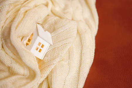 model of a wooden house in a white knitted blanket. Real estate mortgage and insurance concept. Buying or selling property. Financial expensesの写真素材