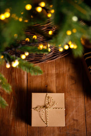 christmas gift in a cardboard box on a brown wooden floor near a new year treeの写真素材