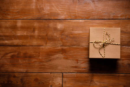 gift in a cardboard box on a brown wooden floor. Simple concept of a surpriseの写真素材