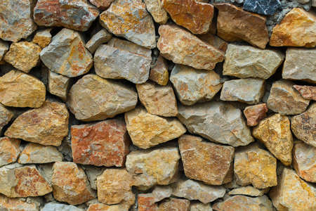 yellow stone fence. Stone masonry from large cobblestones of granite. Natural texture and background, backdropの写真素材