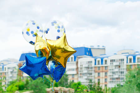 yellow and blue helium balloons on the background of the city. Gift and decoration for a birthday party. Place for text, copy spaceの写真素材
