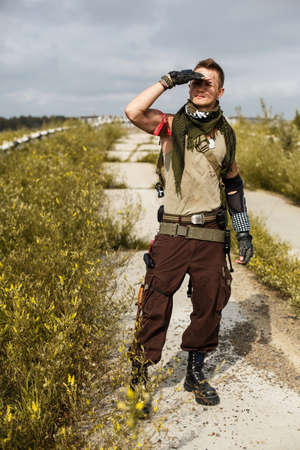 portrait of a male vandal in dirty clothes against the backdrop of an abandoned bridge