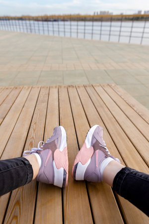 Women's sports shoes on wooden planks. White soles of pink sneakers. View from above