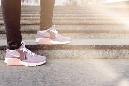 cropped image of female legs in shoes. Woman in pink sneakers descend stairsの写真素材