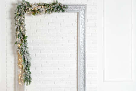 frame decorated with christmas garland on white brick wall backgroundの写真素材