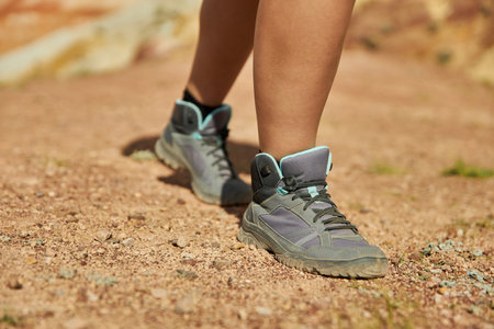woman legs in hiking boots climbs up the sandy hill on a summer day. Tourism, travel and adventureの写真素材