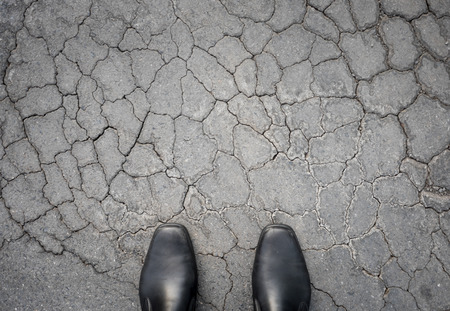 black shoes standing on damaged asphalt concrete floorの写真素材