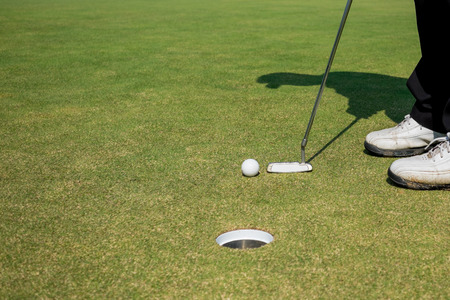 Golfer putting golf ball under sunshine