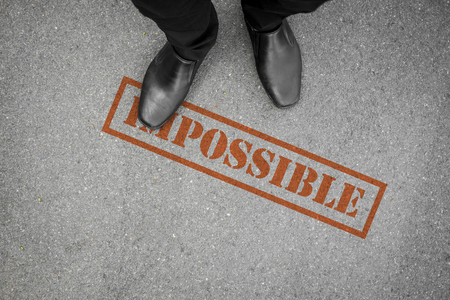 black shoes stepping on impossible word on the floor, making everything possible