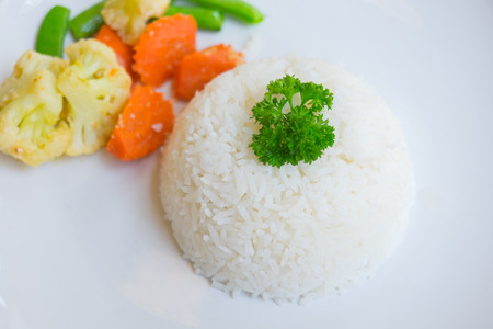 Steamed Thai jasmine rise, boiled broccoli, carrot and peas in white plateの写真素材