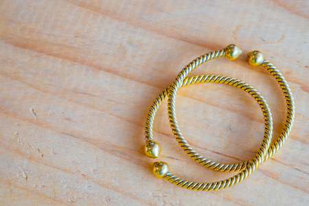 Gold bracelets on wooden table. It's jewelry and fashion for ladiesの写真素材