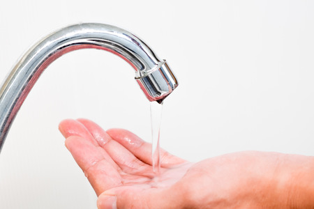 Water pouring from faucet to a hand. saving waterの写真素材