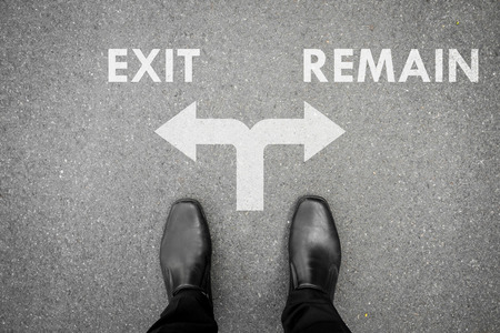 Businessman in black shoes standing at the crossroad making decision which way to go - exit or remainの写真素材