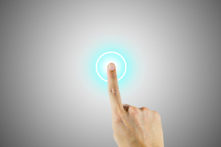 Hand pushing on round button in the center to start, begin, stop or to activate something.