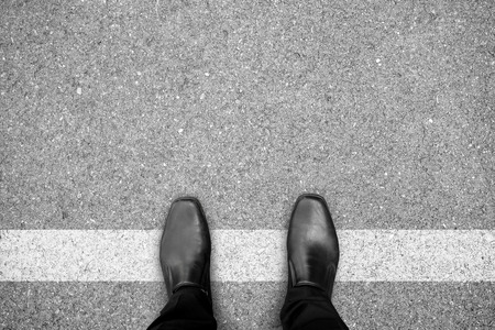 Businessman in black shoes standing on white line. Prohibited and restricted. Crossing border. Think different.の写真素材