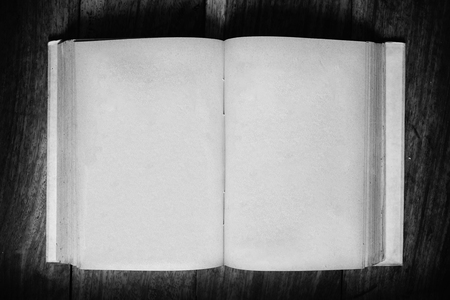 Opened old grunge empty page paper book on wooden table - vintage, black and white effectの写真素材