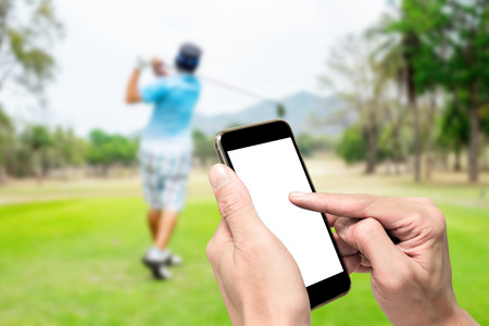 One using smartphone when other swinging on golf teeing ground.の写真素材