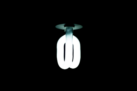 Lightening compact fluorescent bulb in the dark for saving energy.