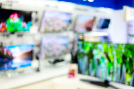 Abstract blur electronic device department in big mall as background. Wide screen televisions showing its colorful.の写真素材