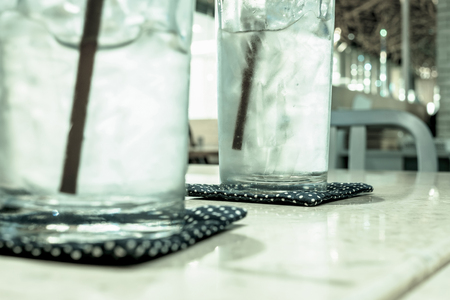 Glasses of cold water and ice served on the table in restaurant. Selective focus on the right glass. Cold filter effect.の写真素材