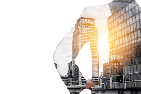 Double exposure back side of businessman standing and akimbo and downtown city building and sunrise or sunset.の写真素材