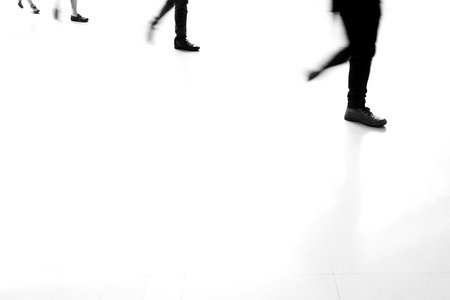 Motion blur people walking on white tiled floor. Walking in a row. Black and white filter.の写真素材