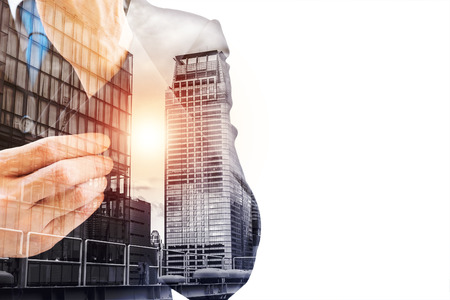 Double exposure of businessman in gray suit button up his left sleeve and urban city in the morning. He is ready to work hard and get success.の写真素材
