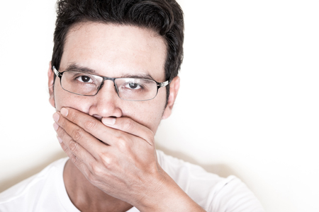 Portrait of Asian man with curly hair and eyeglasses cover his not to speak and keep silence secret.の写真素材