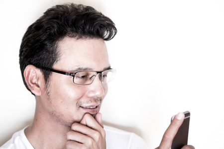 Handsome asian man with light beard and curly hair wearing eyeglasses for near sighted using smartphone.  Smile and happy.の写真素材