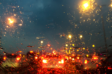 Driving in the rain. Water drops on front glass of the car while raining and very bad traffic on the...